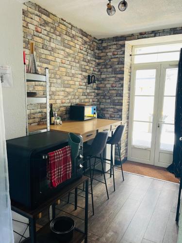 une cuisine avec une table et des chaises ainsi qu'un mur en briques dans l'établissement Comfy Loft - Dalby, à Nantes