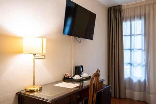 a hotel room with a desk with a television on the wall at Abba Xalet Suites Hotel in Sispony