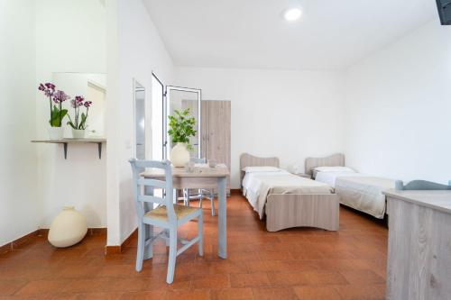 a room with two beds and a table and chairs at Villaggio Residence Emmesse Appartamento Standard in Mandaradoni
