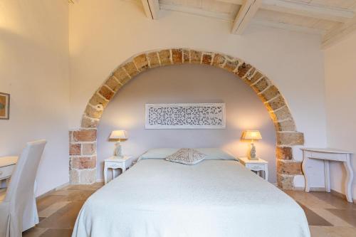 a bedroom with a white bed and two tables at Masseria La Tofala benessere & SPA in Copertino