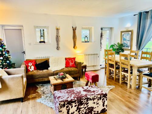 ein Wohnzimmer mit einer Couch und einem Weihnachtsbaum in der Unterkunft Castleford Cottage , Lowermill Estate in Somerford Keynes