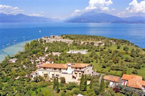 a large house on a hill next to the water at Hotel Ideal in Sirmione