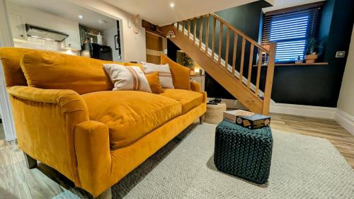 a yellow couch in a living room with a staircase at Cosy Cottage Stay Book & Unwind in Penrith