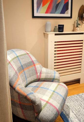 a plaid chair in a living room with a fireplace at Cosy Cottage Stay Book & Unwind in Penrith