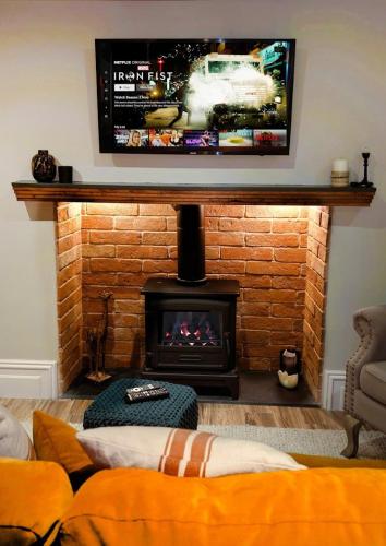 a living room with a fireplace with a tv above it at Cosy Cottage Stay Book & Unwind in Penrith