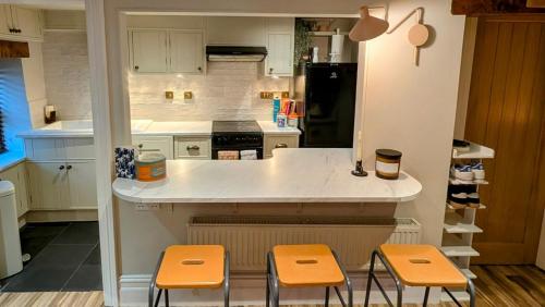 una cucina con bancone e tre sgabelli di Cosy Cottage Stay Book & Unwind a Penrith