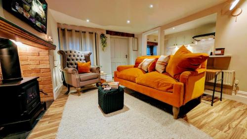 un soggiorno con divano arancione e sedia di Cosy Cottage Stay Book & Unwind a Penrith