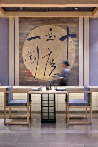 a man sitting at a table with two chairs and a painting at Islamabad Marriott Hotel in Islamabad
