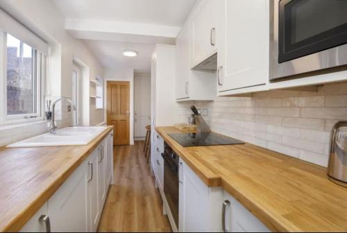 a kitchen with white cabinets and a wooden counter top at 4 bedroom house close to Walmgate bar sleeps 7 in York