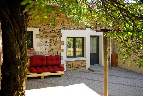 a red couch sitting in front of a brick building at Къщичка Под шарената сянка in Kŭrpachevo
