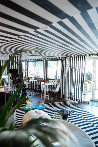 a room with a striped ceiling with tables and chairs at O Petit Monde in Sanary-sur-Mer