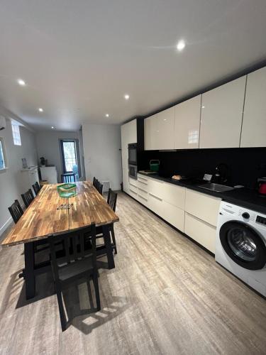 une cuisine avec une table en bois et un lave-linge dans l'établissement Chez Edouard - Superbe Triplex neuf - 6 chambres - Centre ville proche Rotonde allées provençales, à Aix-en-Provence
