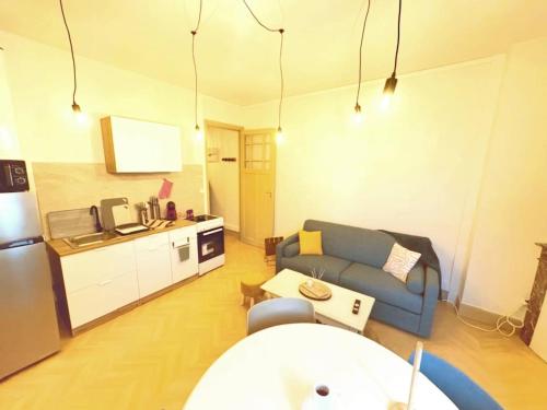 un salon avec un canapé bleu et une cuisine dans l'établissement Appartement cosy au cœur de Saint Quentin, à Saint-Quentin