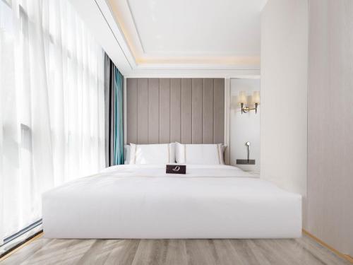 a large white bed in a room with a large window at Pazhou XANA Deluxe International Hotel Pazhou Convention and Exhibition Center Nanzhou Metro Station Branch - Free Shuttle Bus to Canton Fair Complex During Canton Fair Period in Guangzhou