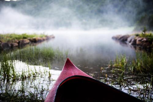 ein Blick von der Rückseite eines Paddelboots in einem Fluss in der Unterkunft Arctic photo retreat Lofoten - lakehouse Bjørkly in Vestvågøya