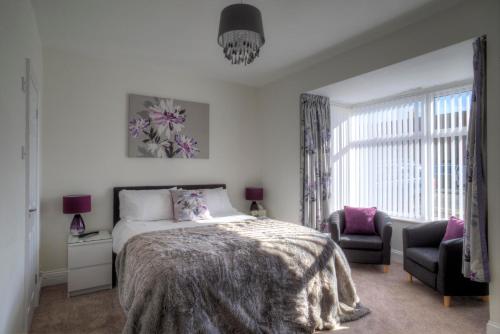 a bedroom with a bed and a chair and a window at Dunelm House in Seahouses