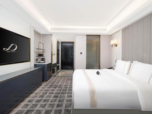 a hotel room with a large white bed and a flat screen tv at Pazhou XANA Deluxe International Hotel Pazhou Convention and Exhibition Center Nanzhou Metro Station Branch - Free Shuttle Bus to Canton Fair Complex During Canton Fair Period in Guangzhou