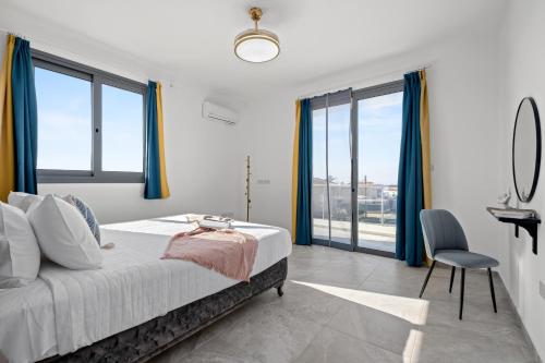 a bedroom with a bed and a desk and windows at Eden Blue Villa by Nomads in Emba