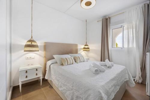 ein weißes Schlafzimmer mit einem Bett mit zwei Handtüchern darauf in der Unterkunft Isla Candor free parking by Staycare in Rota