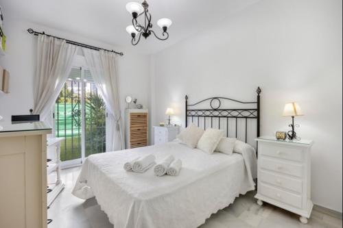 a white bedroom with a large white bed with two towels at Paraíso del golf free parking by Staycare in Rota