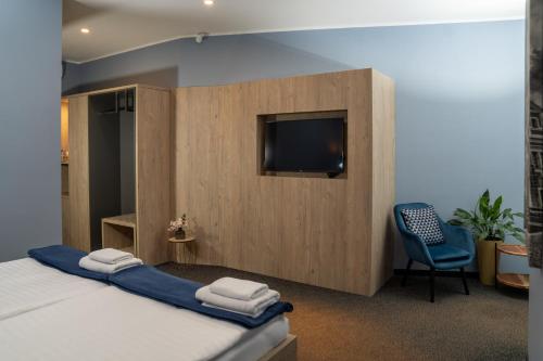 a bedroom with a bed and a tv and a chair at Hotel Grunt in Mladá Boleslav