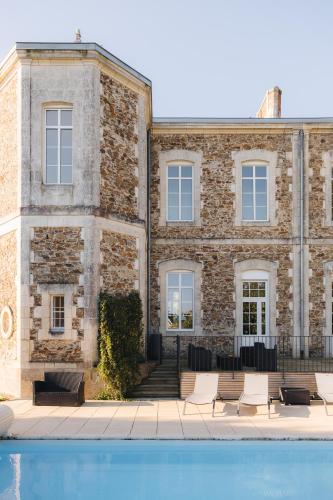 un bâtiment avec une piscine devant dans l'établissement La Maison D'Olivier, à Mesnard-la-Barotière