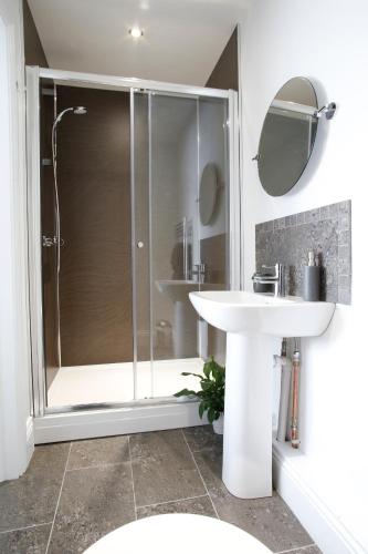 a bathroom with a shower and a white sink at Dunelm House in Seahouses