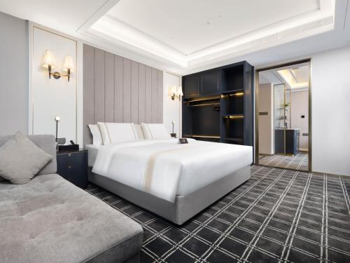 a bedroom with a large white bed and a couch at Pazhou XANA Deluxe International Hotel Pazhou Convention and Exhibition Center Nanzhou Metro Station Branch - Free Shuttle Bus to Canton Fair Complex During Canton Fair Period in Guangzhou