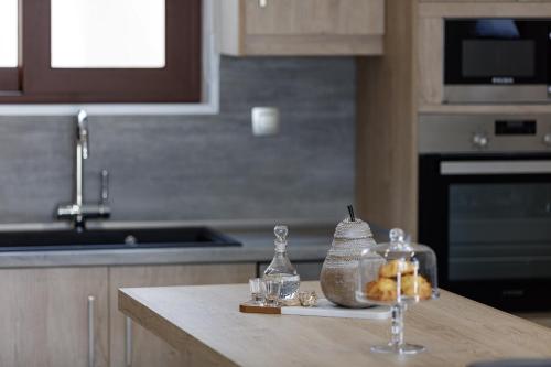 a kitchen with a counter with glasses and bottles on it at Villa Fotinou Heated Pool & Free Bikes awaits in Fotinós