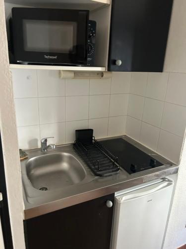 une petite cuisine avec un évier et un micro-ondes dans l'établissement Appartement T2 Port Marianne, à Montpellier