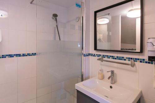 une salle de bain avec une douche, un lavabo et un miroir dans l'établissement Hotel Geoffroy Marie Opéra, à Paris