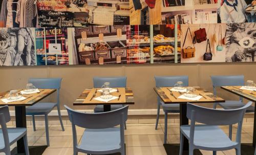 un restaurant avec des tables en bois et des chaises bleues dans l'établissement Hotel Geoffroy Marie Opéra, à Paris