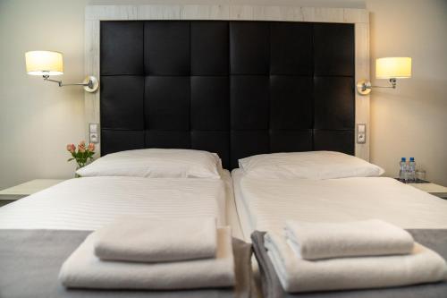 two beds in a bedroom with a black headboard at Hotel Grunt in Mladá Boleslav