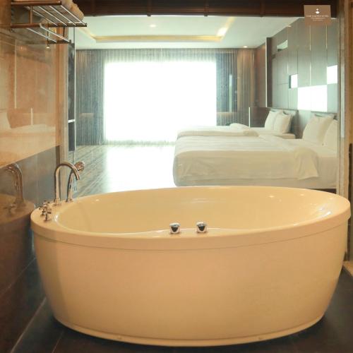 a large bath tub in a room with a bed at โรงแรม อีส จอมเทียน บี in Jomtien Beach