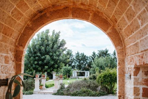 an archway with a view of a garden through it at Masseria La Tofala benessere & SPA in Copertino