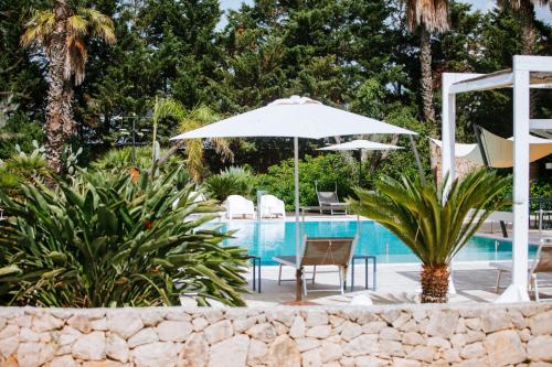 a pool with a table and an umbrella and chairs at Masseria La Tofala benessere & SPA in Copertino