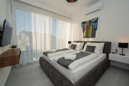a bedroom with a large bed and a large window at Elegant Villa Cataleya with private pool and sauna in Novalja