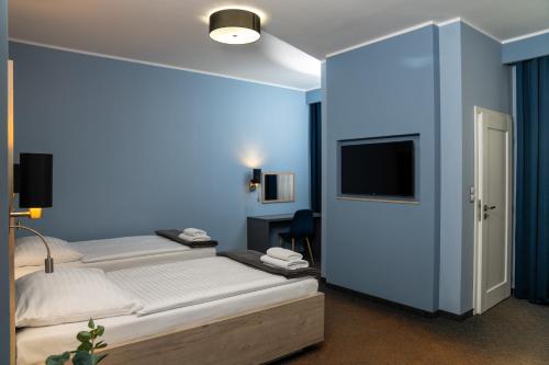 a bedroom with two beds and a blue wall at Hotel Grunt in Mladá Boleslav