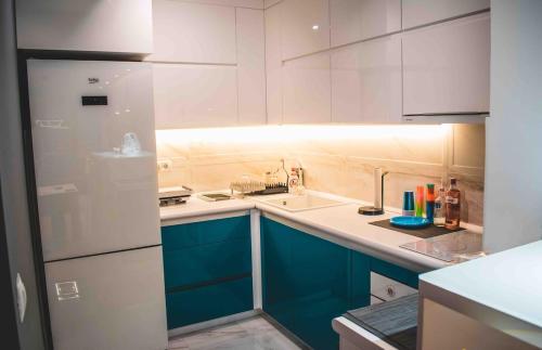 a kitchen with blue cabinets and a white refrigerator at Luxury S&S panoramic city view apartment in Skopje