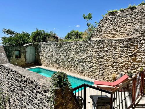 une piscine dans un mur en pierre avec une table et une chaise dans l'établissement La Villa 1777, à Lagnes