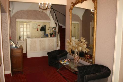 ein Wohnzimmer mit einem Spiegel, einem Tisch und Stühlen in der Unterkunft Cit'Hotel Hôtel Beauséjour in Cherbourg en Cotentin