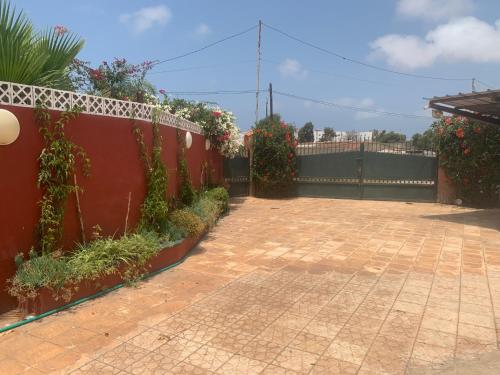 a courtyard with a red fence and some plants at Villa luxueuse à Skhirat Rabat in Skhirat