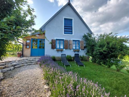 a white house with blue doors and chairs in the yard at Spaletta in Pécsely