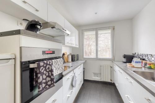 une cuisine avec des armoires blanches et un four à plaques de cuisson dans l'établissement Bel appartement pour 8 personnes à 15 minutes CDG, à Saint-Denis