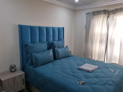 a blue bed with blue pillows in a bedroom at Eazistay Motel - Letlhabile in Brits