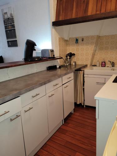 une cuisine avec des armoires blanches et un comptoir dans l'établissement relais du 21, à Saint-Germain-en-Laye