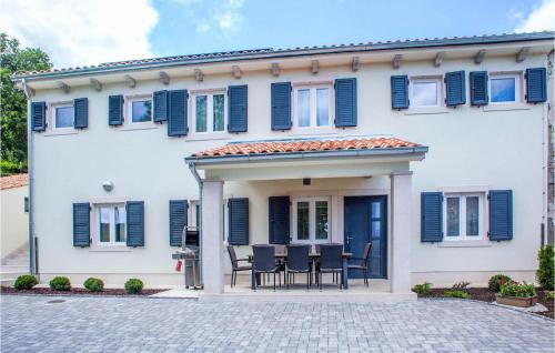a white house with blue shutters and a patio at Villa Orljak in Buzet