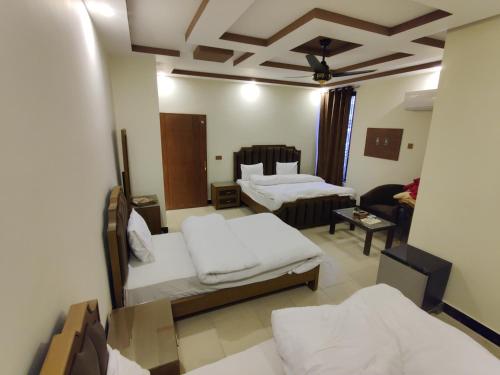 a living room with two beds and a couch at AL Fateh Hotel in Lahore