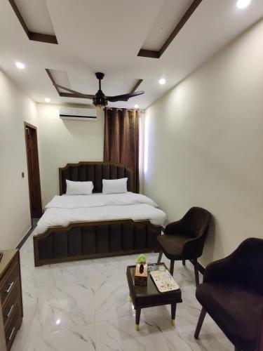 a bedroom with a bed and a chair and a table at AL Fateh Hotel in Lahore