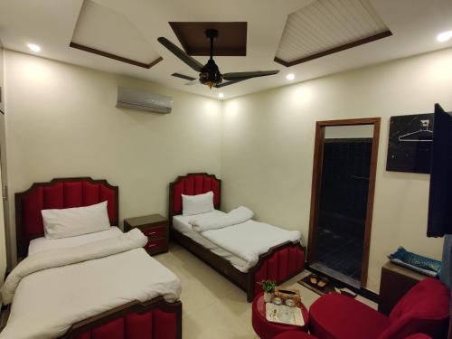 a room with two beds and a couch and a fan at AL Fateh Hotel in Lahore